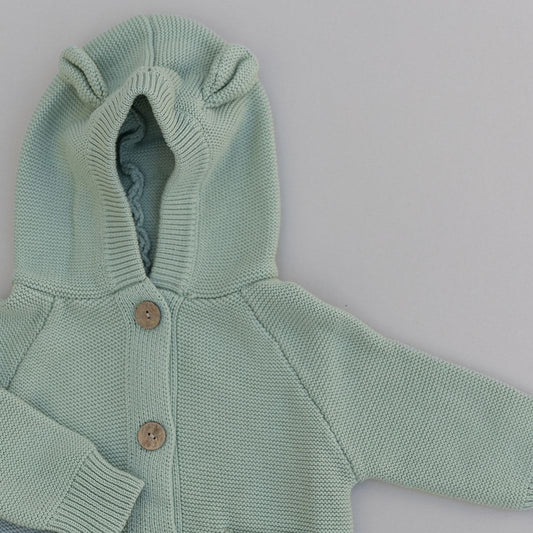 Light green knitted baby cardigan with hood and baby bear ears with buttons on a white background