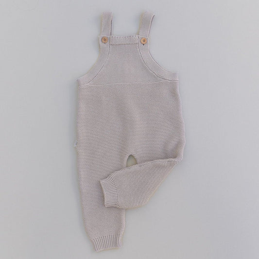 Knitted baby romper in oat on a light gray background