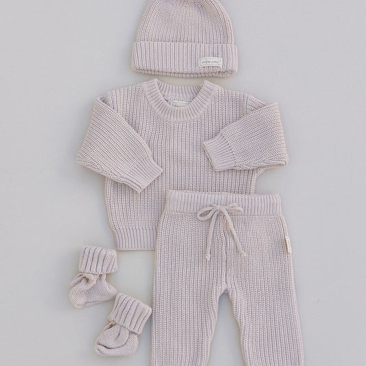 Baby outfit set with sweater, pants, hat, and booties on a light gray background