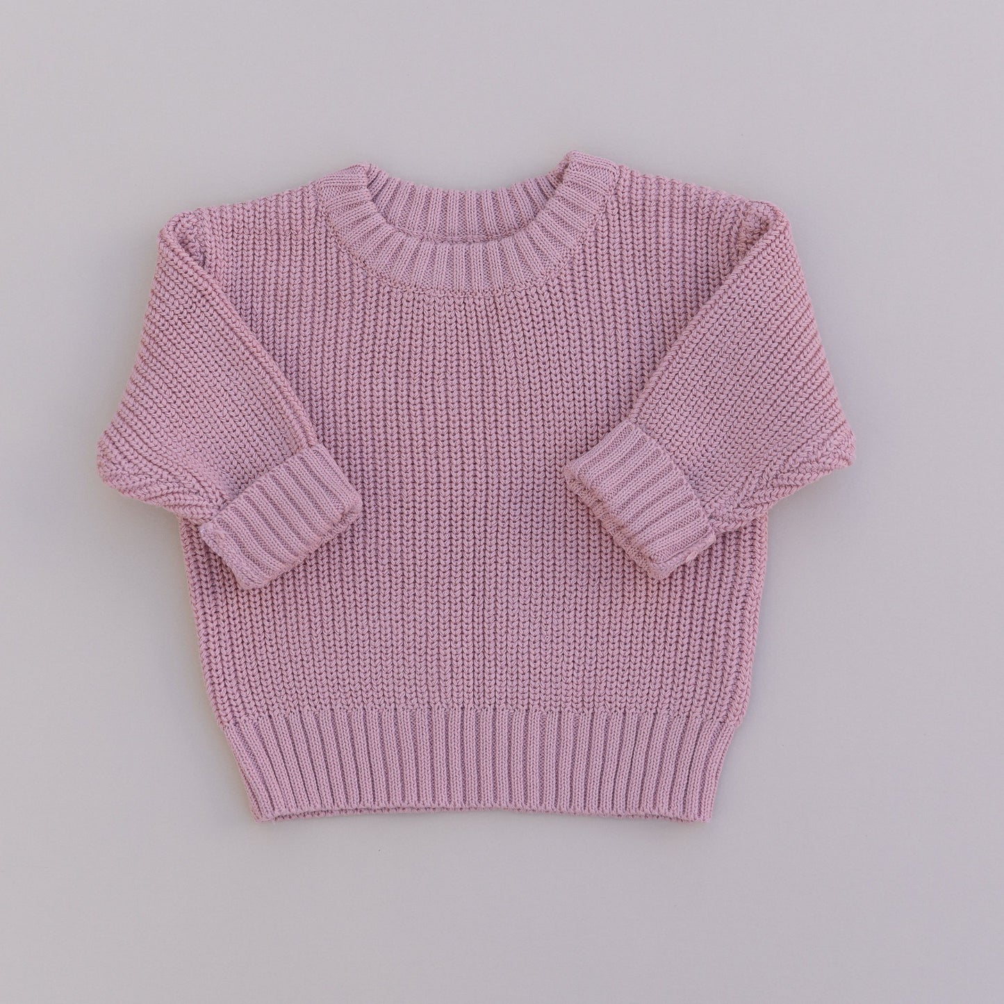 A pink organic cotton knit sweater for babies, displayed against a white background.