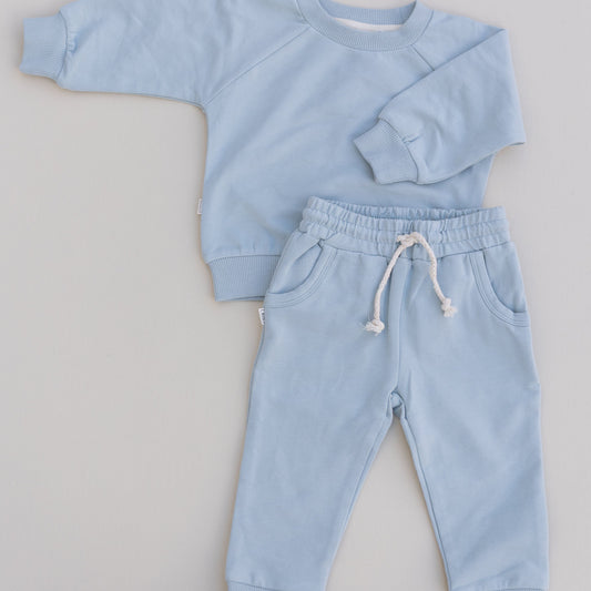 A baby jogger set in blue, including a long-sleeved top and matching pants, laid flat on a white background.