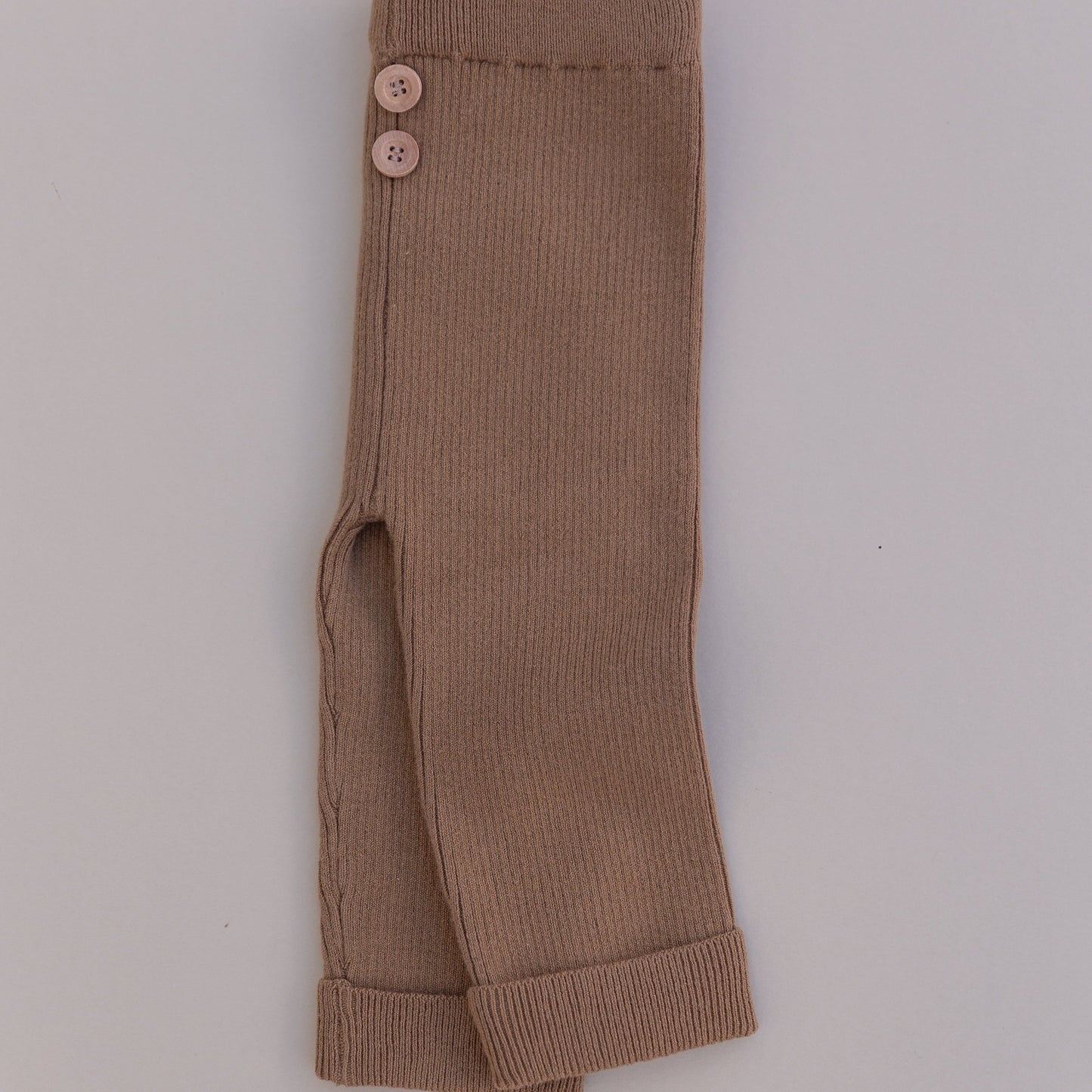 A pair of brown organic cotton leggings with buttons at the waist, folded and laid flat on a white background.