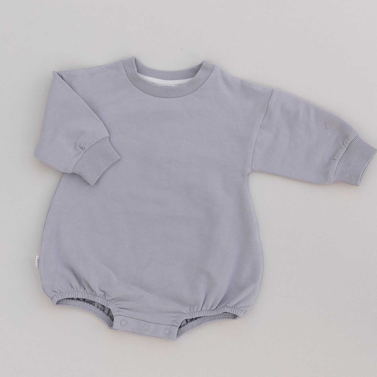 Grey long sleeved baby romper on a light gray background