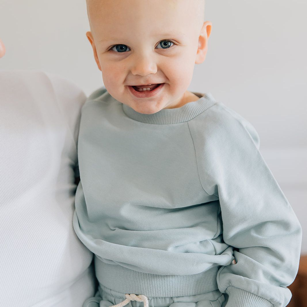 Child wearing a light blue jogger set on a neutral background