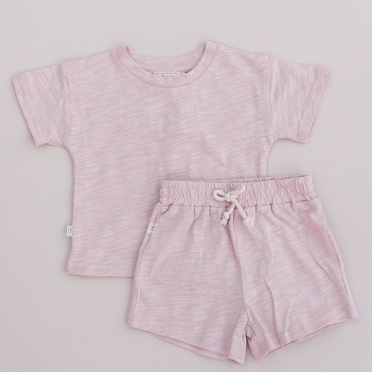 Pink t-shirt and shorts set on a light gray background