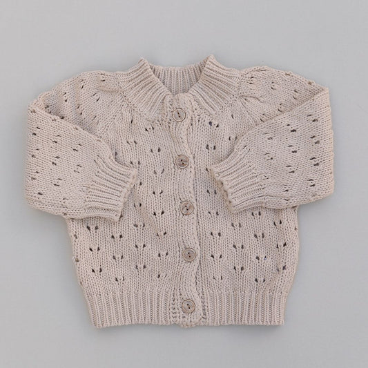 Chunky knitted baby sweater with button details on a gray background