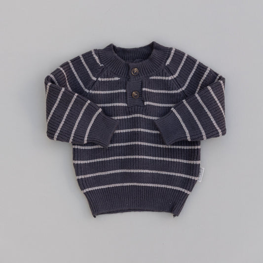 A striped knit button sweater for babies, predominantly in a dark color with light stripes and two front buttons, laid flat on a white background.