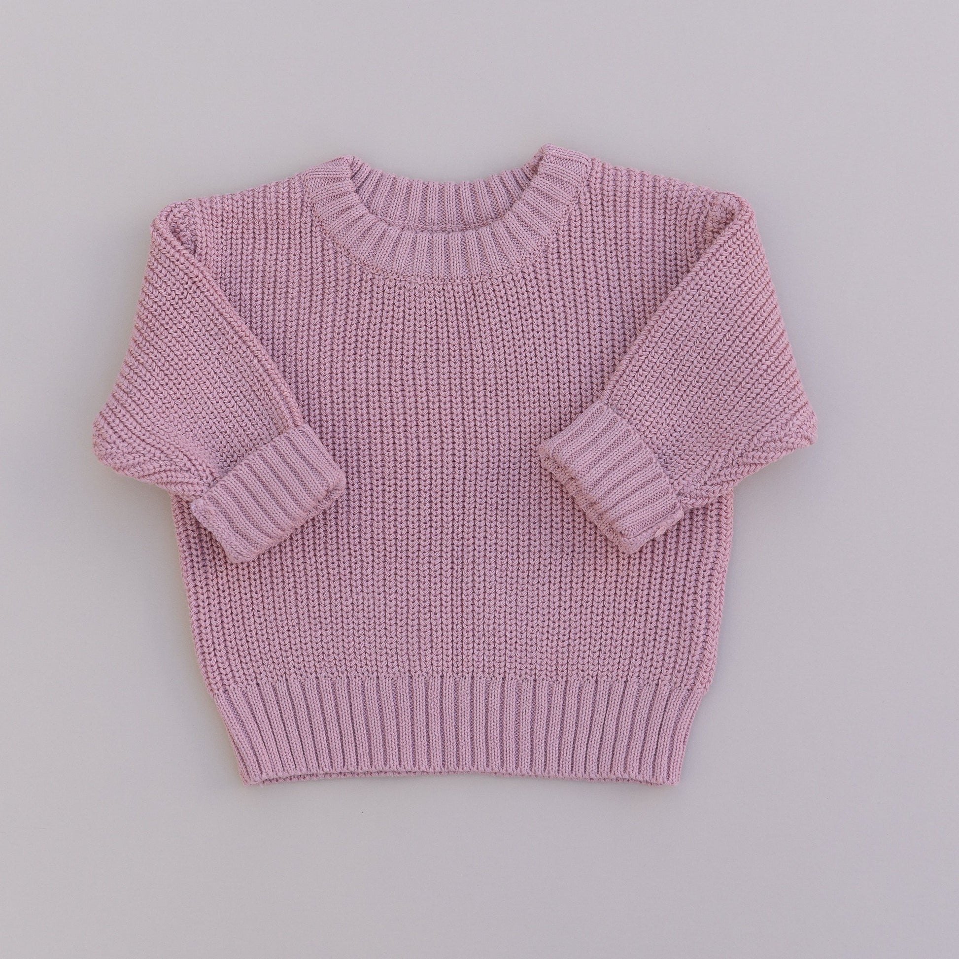 A pink organic cotton knit sweater for babies, displayed against a white background.