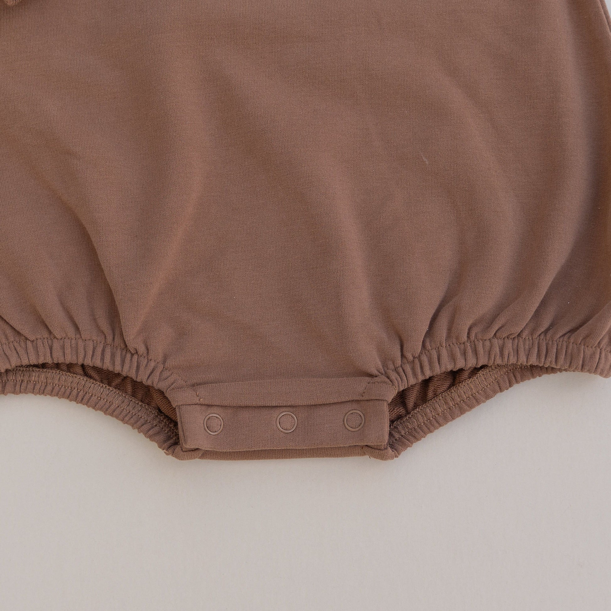 Brown baby romper on a light gray background