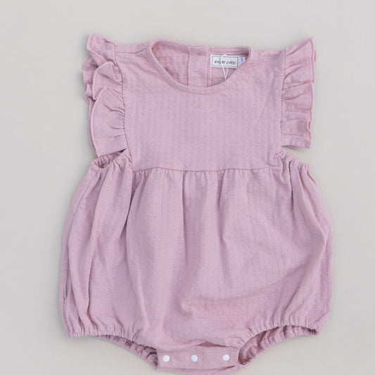 A pink ruffled bubble onesie with short sleeves and snap closures on the bottom for a baby.