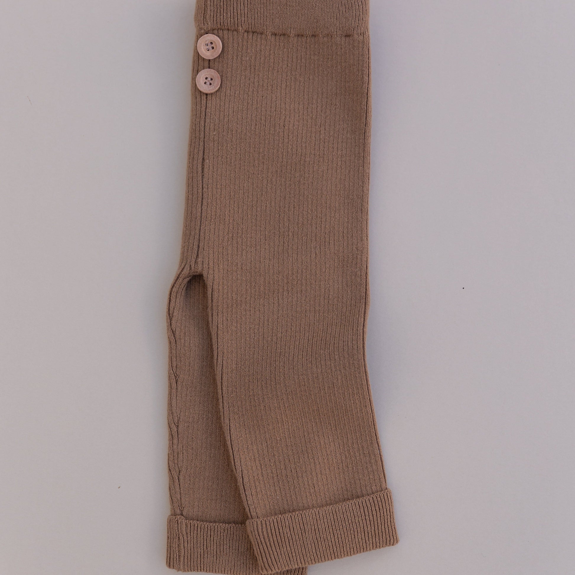 A pair of brown organic cotton leggings with buttons at the waist, folded and laid flat on a white background.
