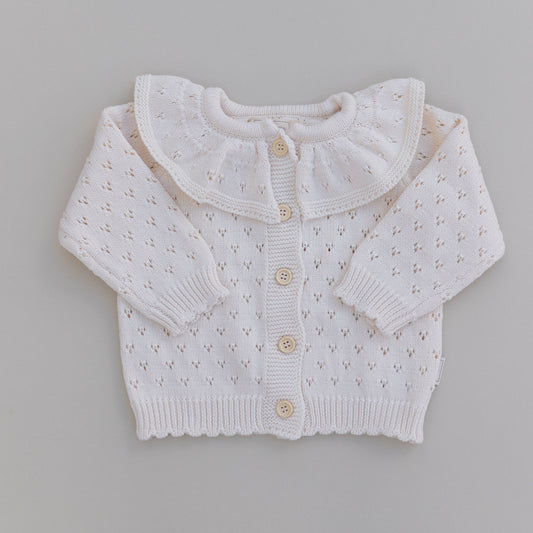 A cream ruffle neck pointelle cardigan with button-down front, laid flat on a neutral background.