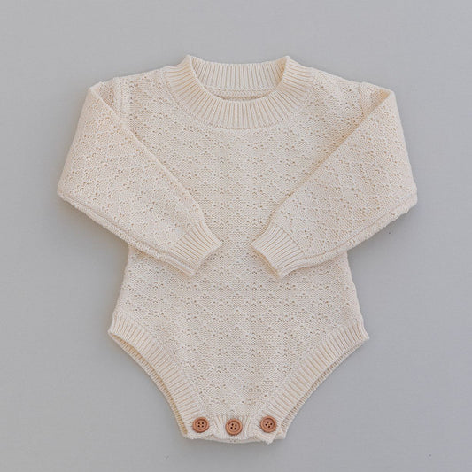 Pointelle knitted long sleeved baby romper  in cream with buttons on a gray background
